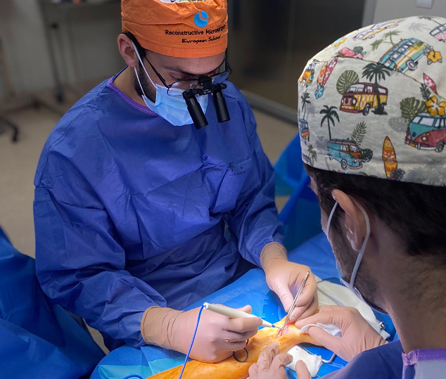 Dos doctores en quirofáno realizan una operación en la muñeca de un paciente.