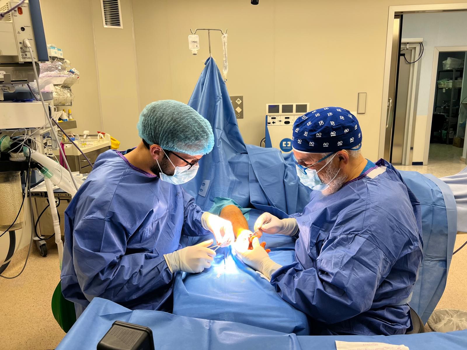 Dos doctores con pijama azul realizando una intervención en quirófano